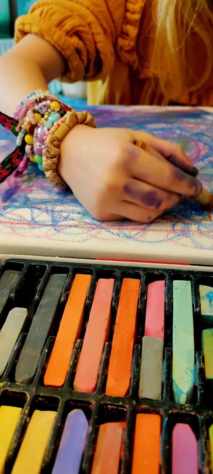 Een kind tekent met pastelkrijt tijdens een creatieve oefening.